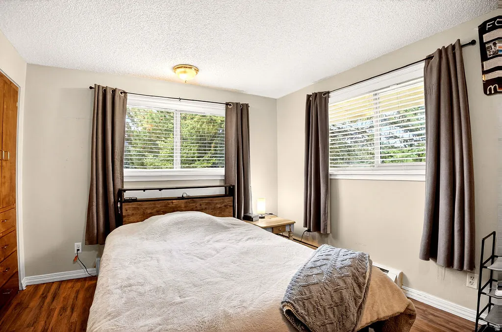 Bedroom featuring dark wood-style flooring, a textured ceiling, and baseboard heating