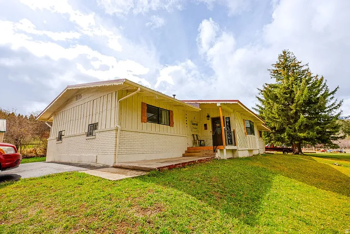 View of front of house featuring brick siding, a front lawn, and board and batten siding