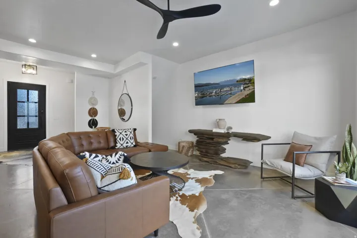 Living room featuring finished concrete floors, recessed lighting, and ceiling fan