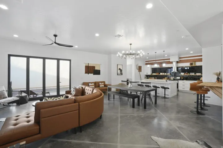 Living room with concrete flooring, hanging lights, and a ceiling fan