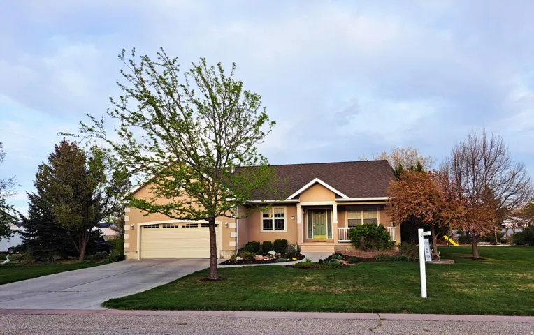 Ranch-style home with a front yard, concrete driveway, a garage, stucco siding, and roof with shingles