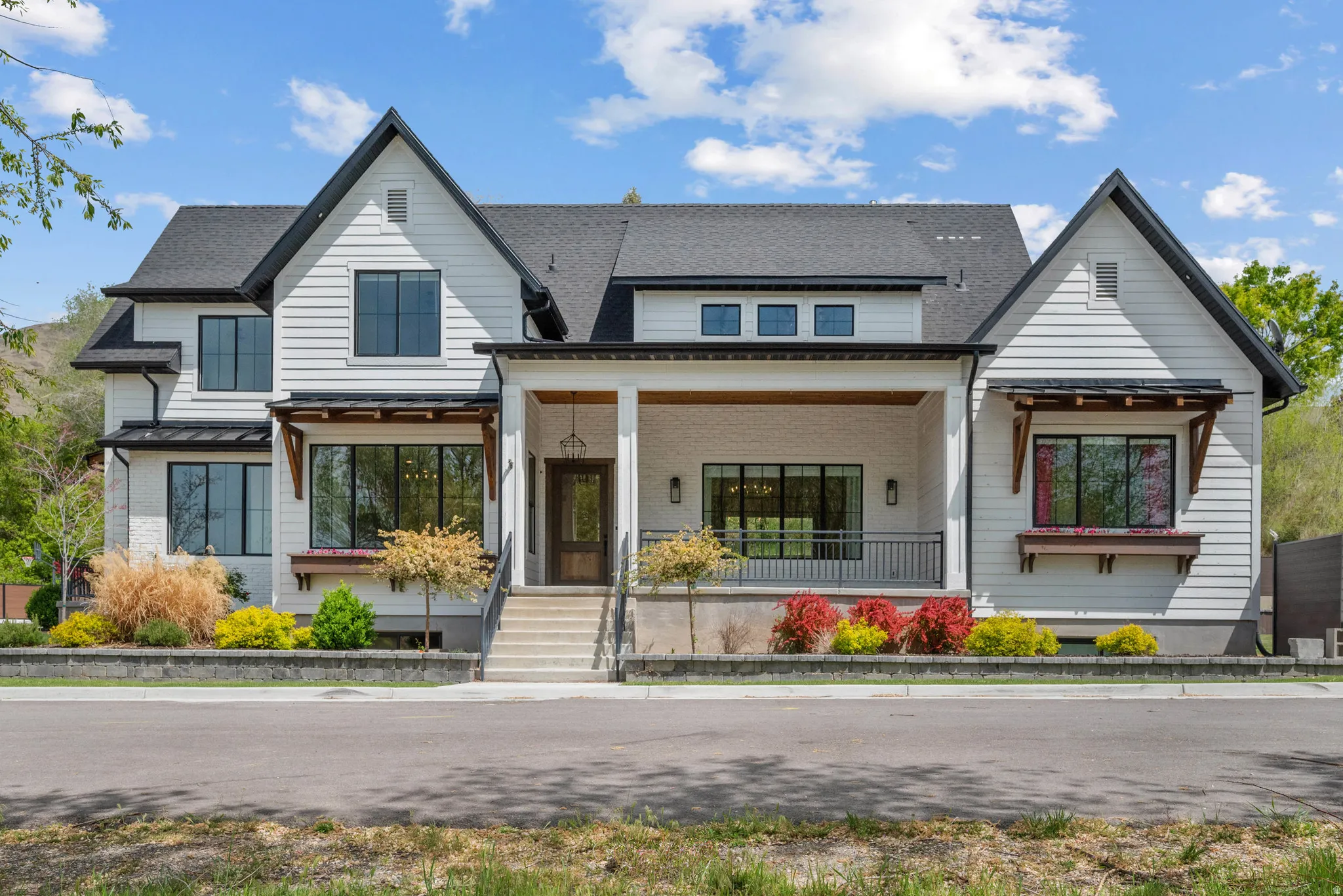 Modern farmhouse style home featuring covered porch, a standing seam roof, brick siding, and roof with shingles