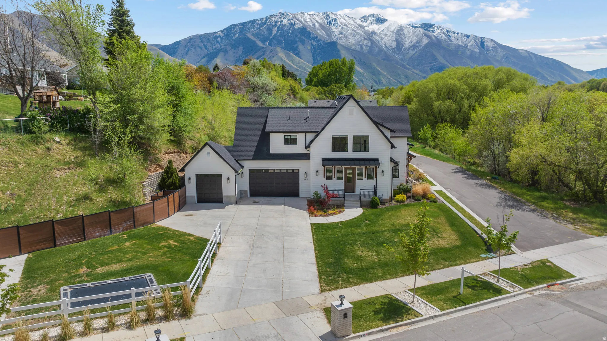 Modern farmhouse style home with concrete driveway, a fenced front yard, a mountain view, and an attached garage