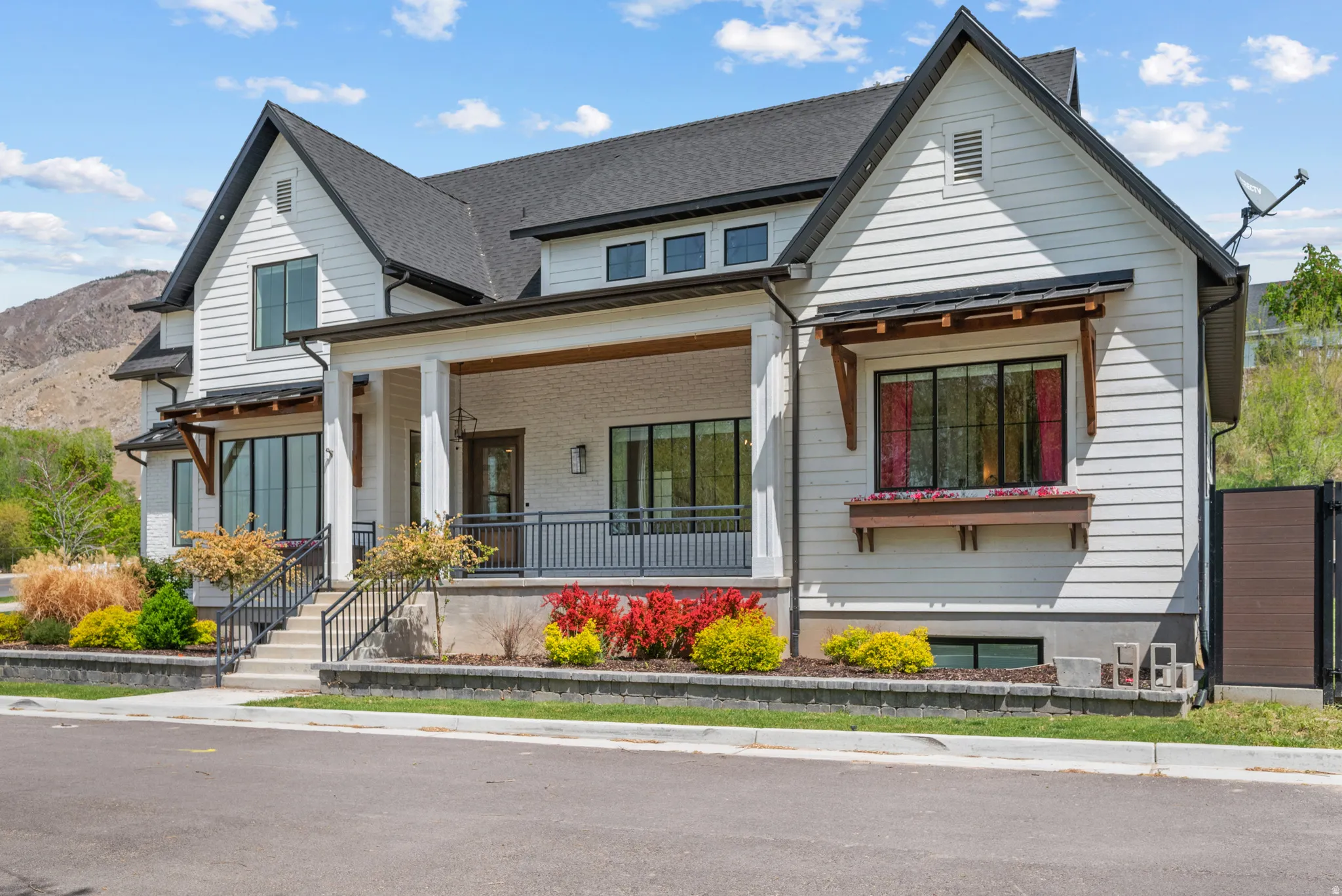 Modern farmhouse with a porch, a shingled roof, a mountain view, and brick siding