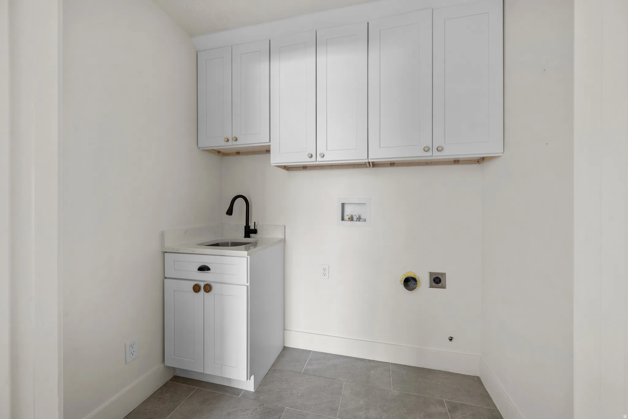 Laundry area featuring cabinet space, hookup for a washing machine, hookup for an electric dryer, and light tile patterned floors