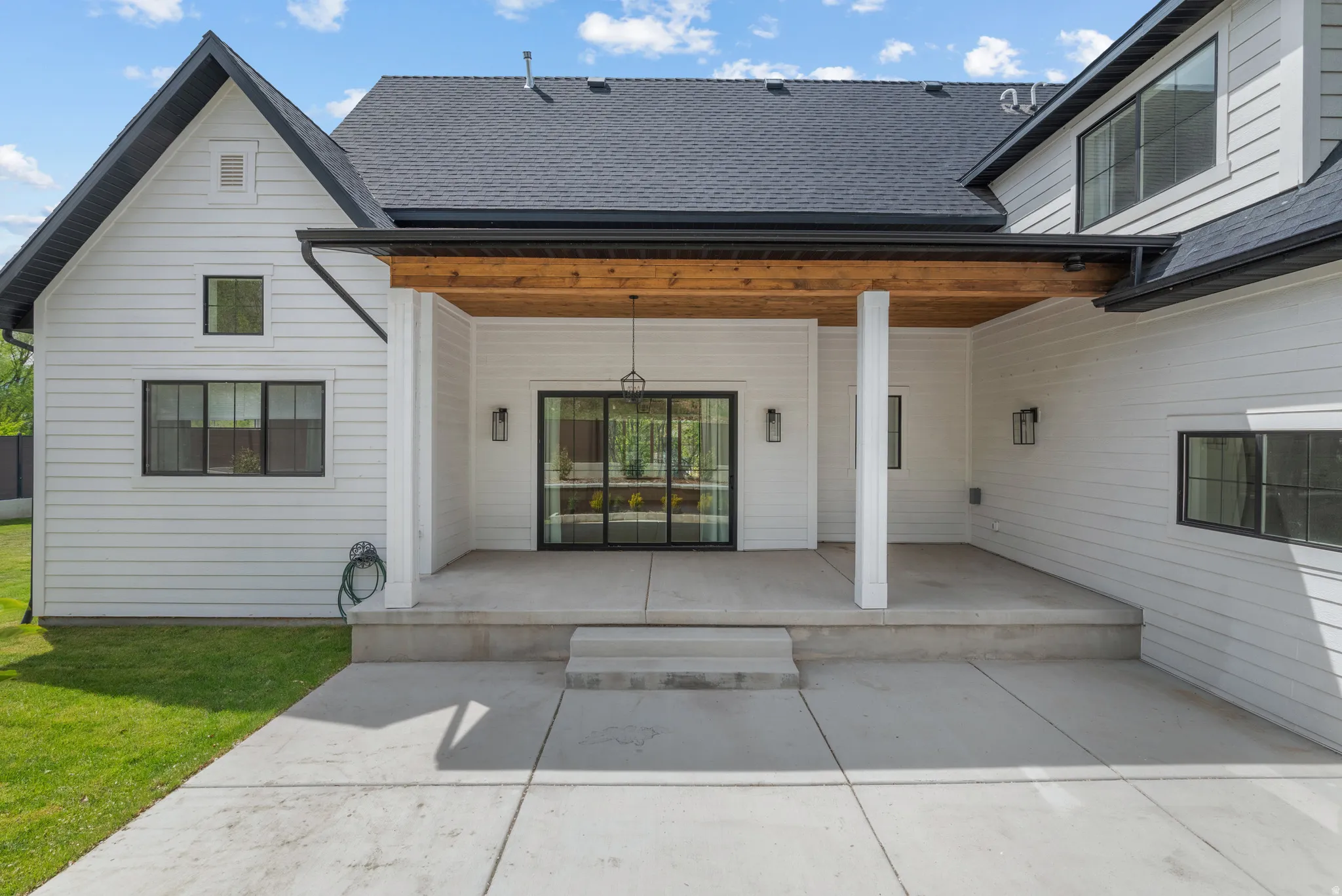 Back of property with a shingled roof and a patio