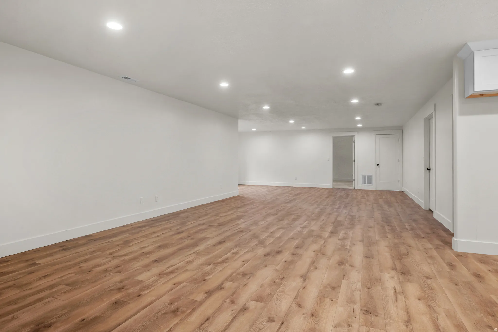 Finished basement with light wood-type flooring and recessed lighting