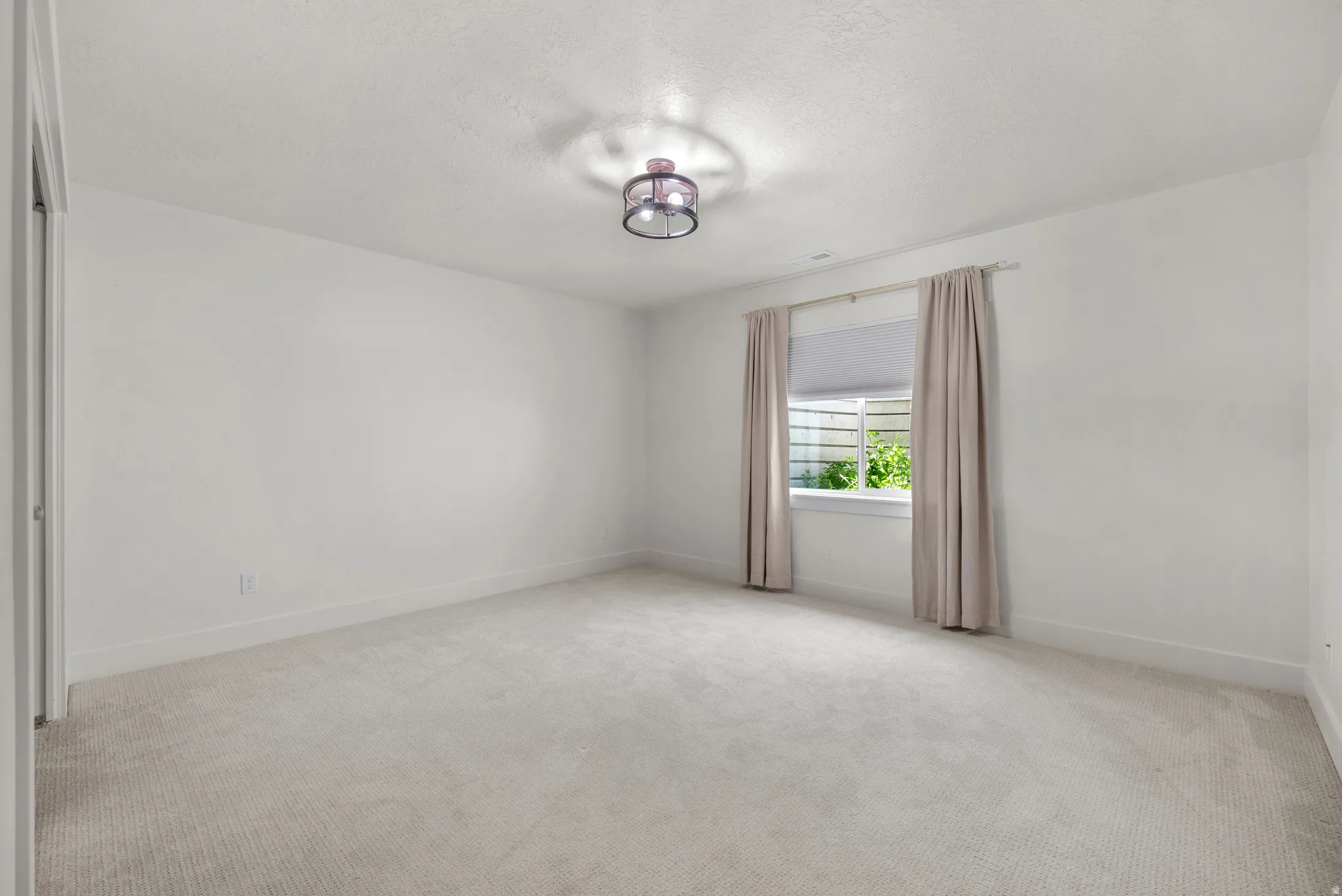 Spare room with a textured ceiling and light carpet