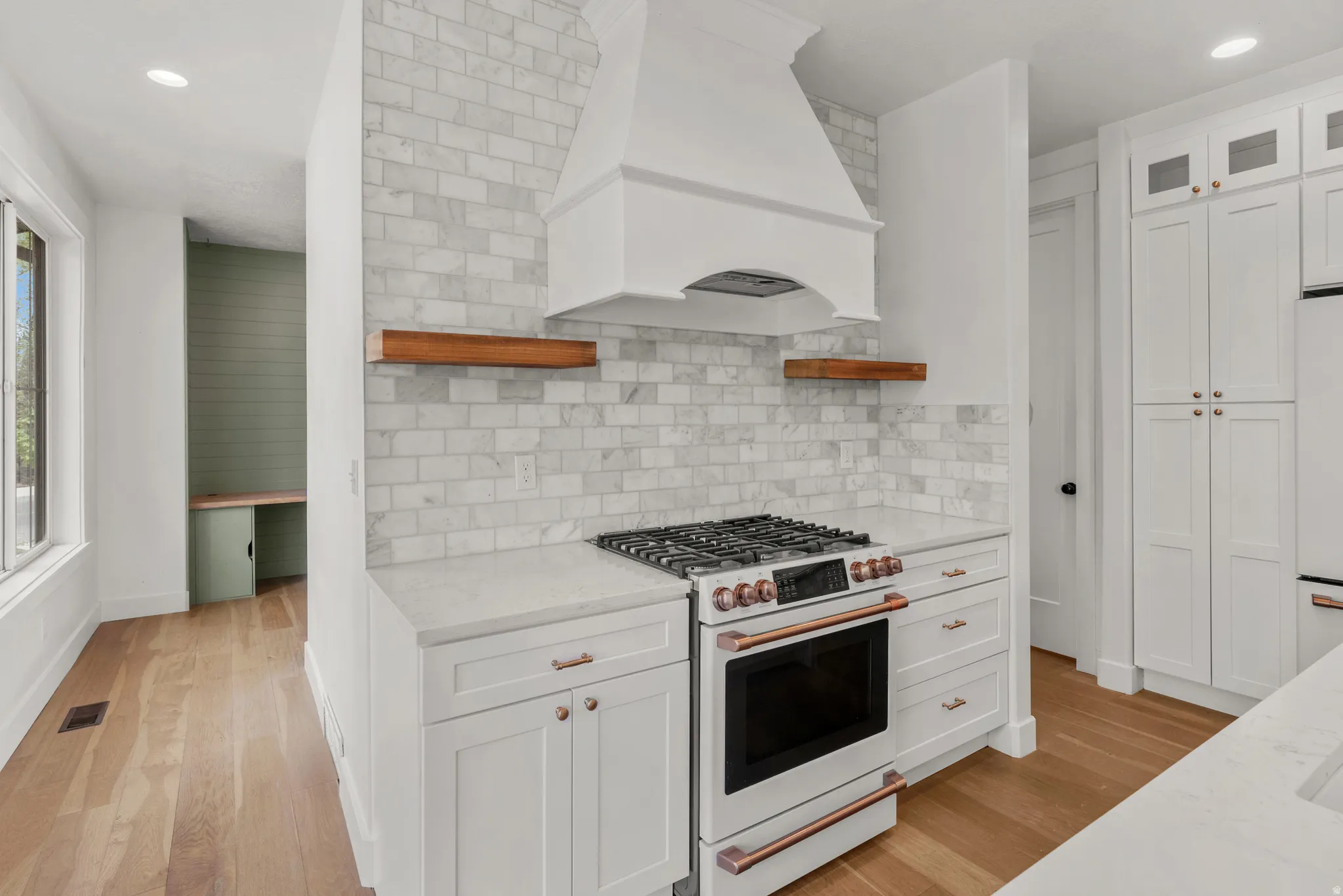 Kitchen with recessed lighting, white appliances, white cabinetry, open shelves, and light stone countertops