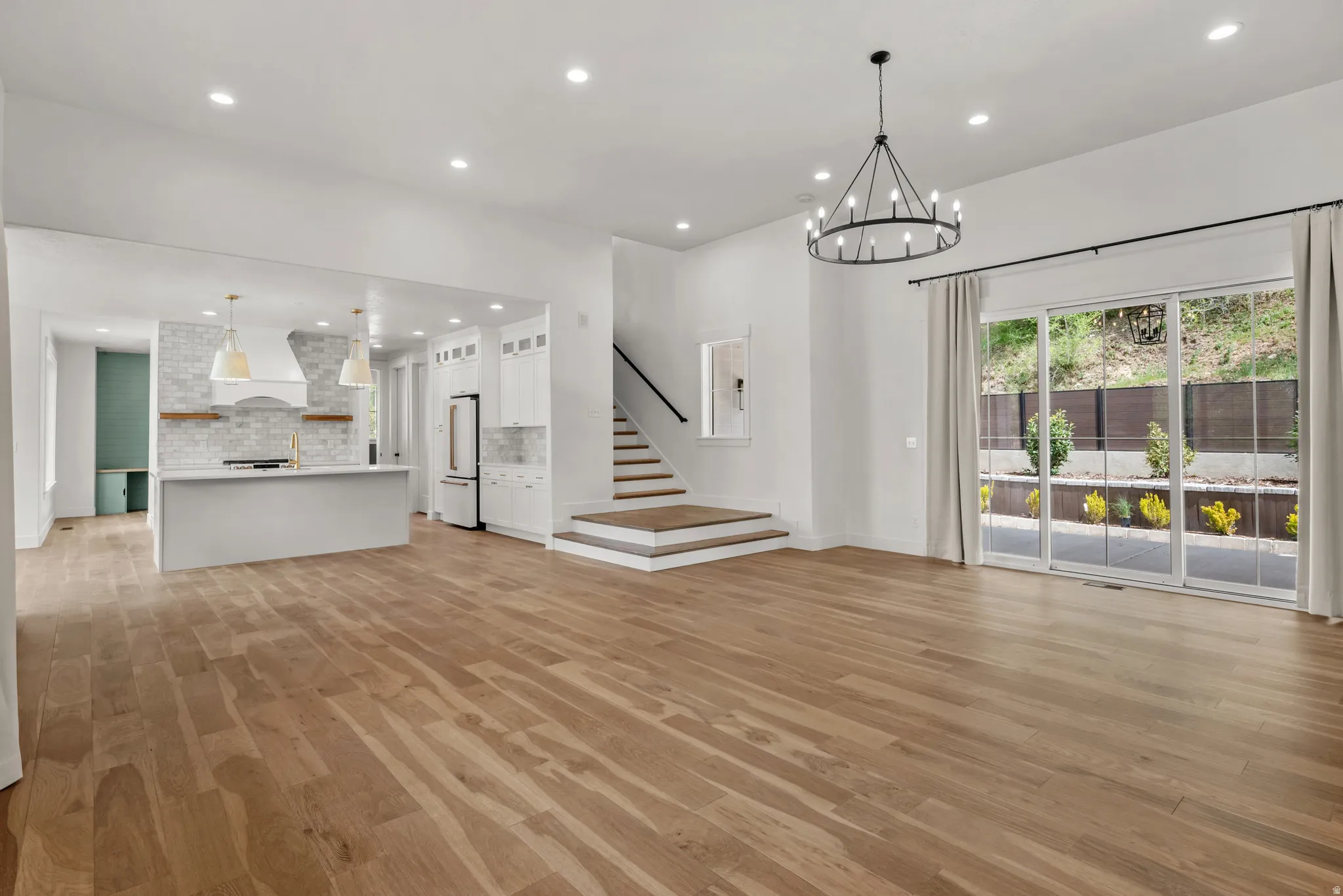 Unfurnished living room with light wood-style flooring and suspended lighting