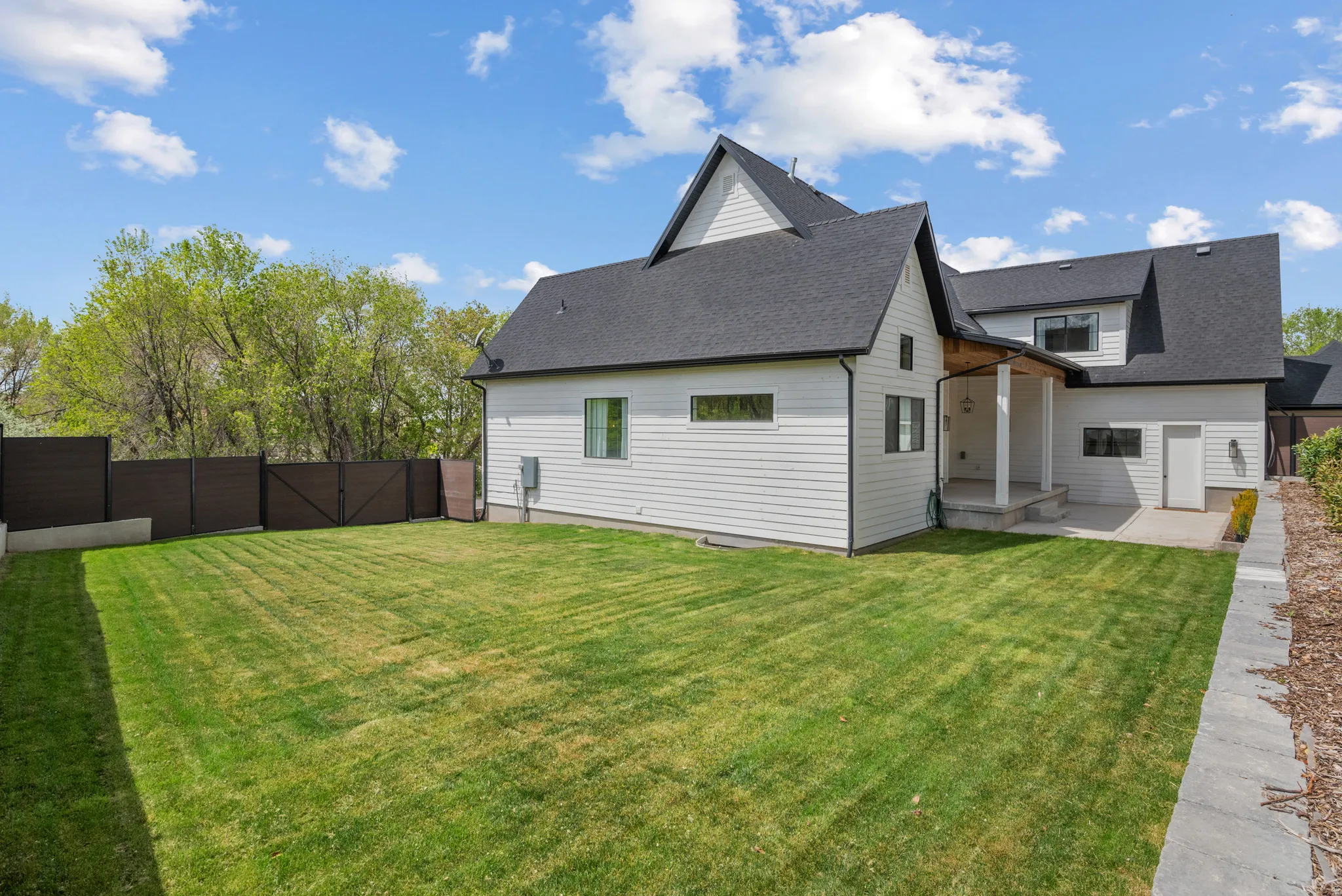 Rear view of house featuring a fenced backyard, a patio, roof with shingles, and a gate