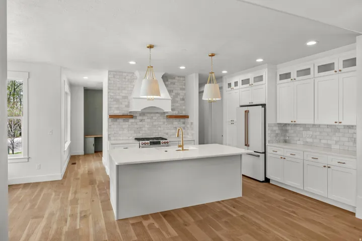 Kitchen with open shelves, pendant lighting, glass fronted cabinets, premium appliances, and a center island with sink