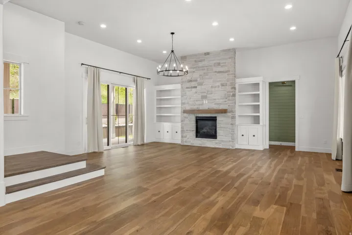 Unfurnished living room featuring dark wood-type flooring, a chandelier, and a fireplace