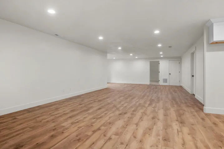 Finished basement with light wood-type flooring and recessed lighting
