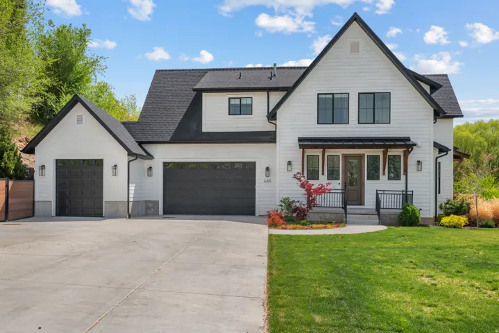 Modern inspired farmhouse featuring a front lawn, driveway, a shingled roof, and an attached garage