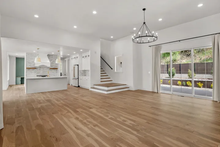 Unfurnished living room with light wood-style flooring and suspended lighting