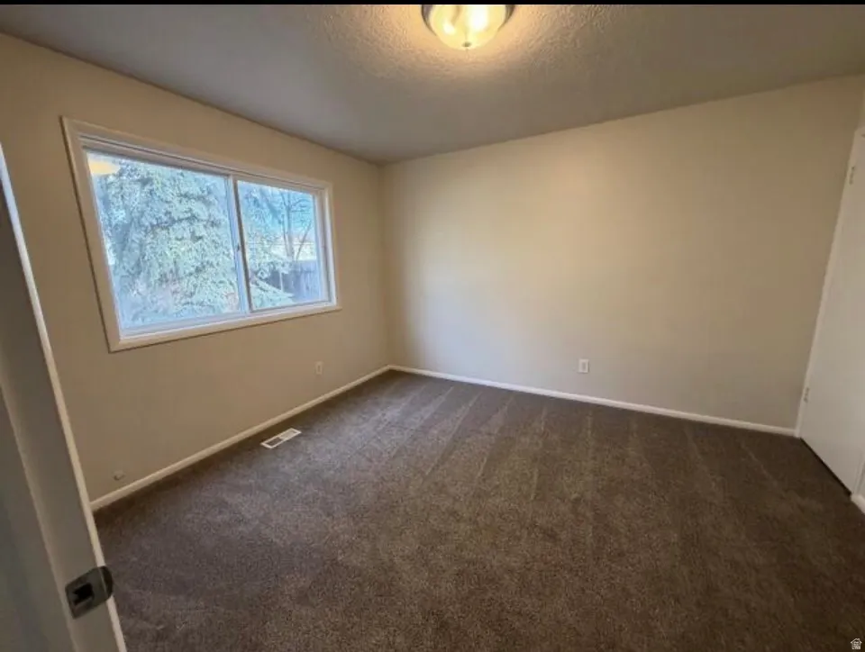 Spare room with dark carpet and a textured ceiling