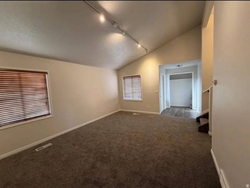 Unfurnished room with track lighting and dark carpet