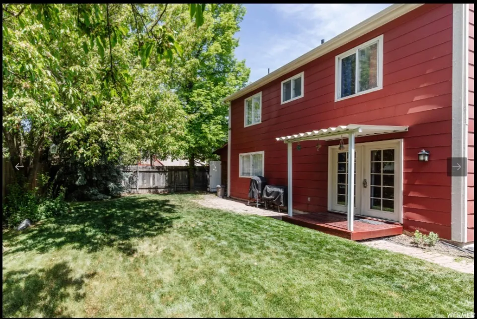 Rear view of property with a fenced backyard, a deck, and french doors