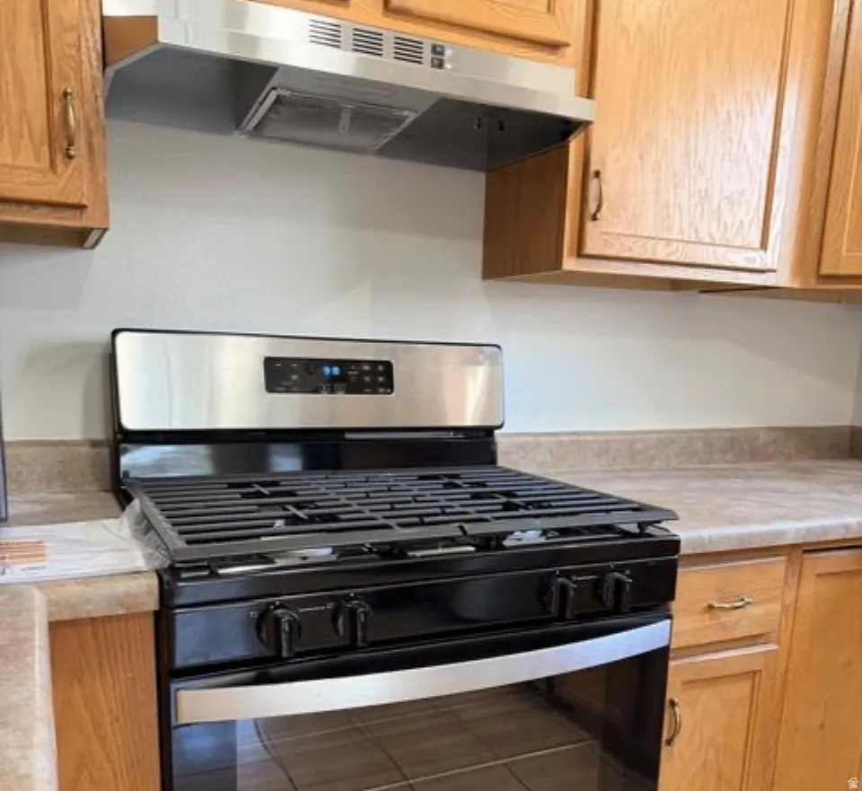 Kitchen with stainless steel gas stove, light countertops, and wood finish cabinetry
