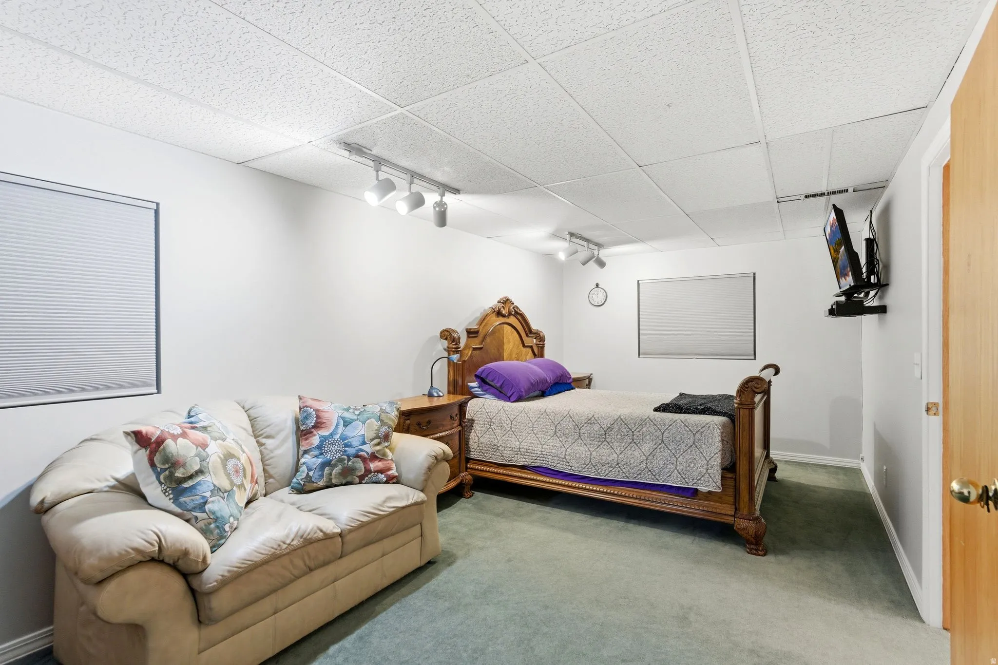 Carpeted bedroom with rail lighting and a paneled ceiling
