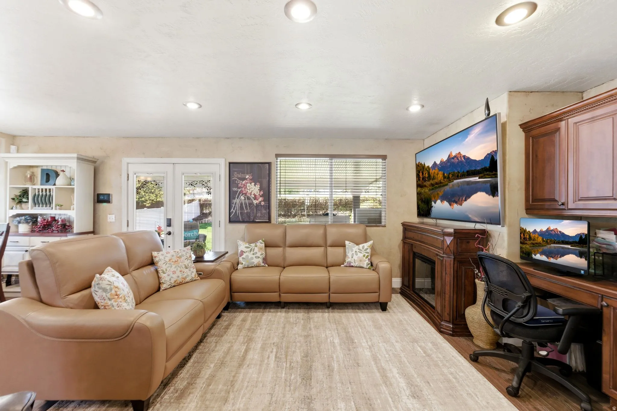 Living room with an office area, a glass covered fireplace, french doors, recessed lighting, and light wood finished floors