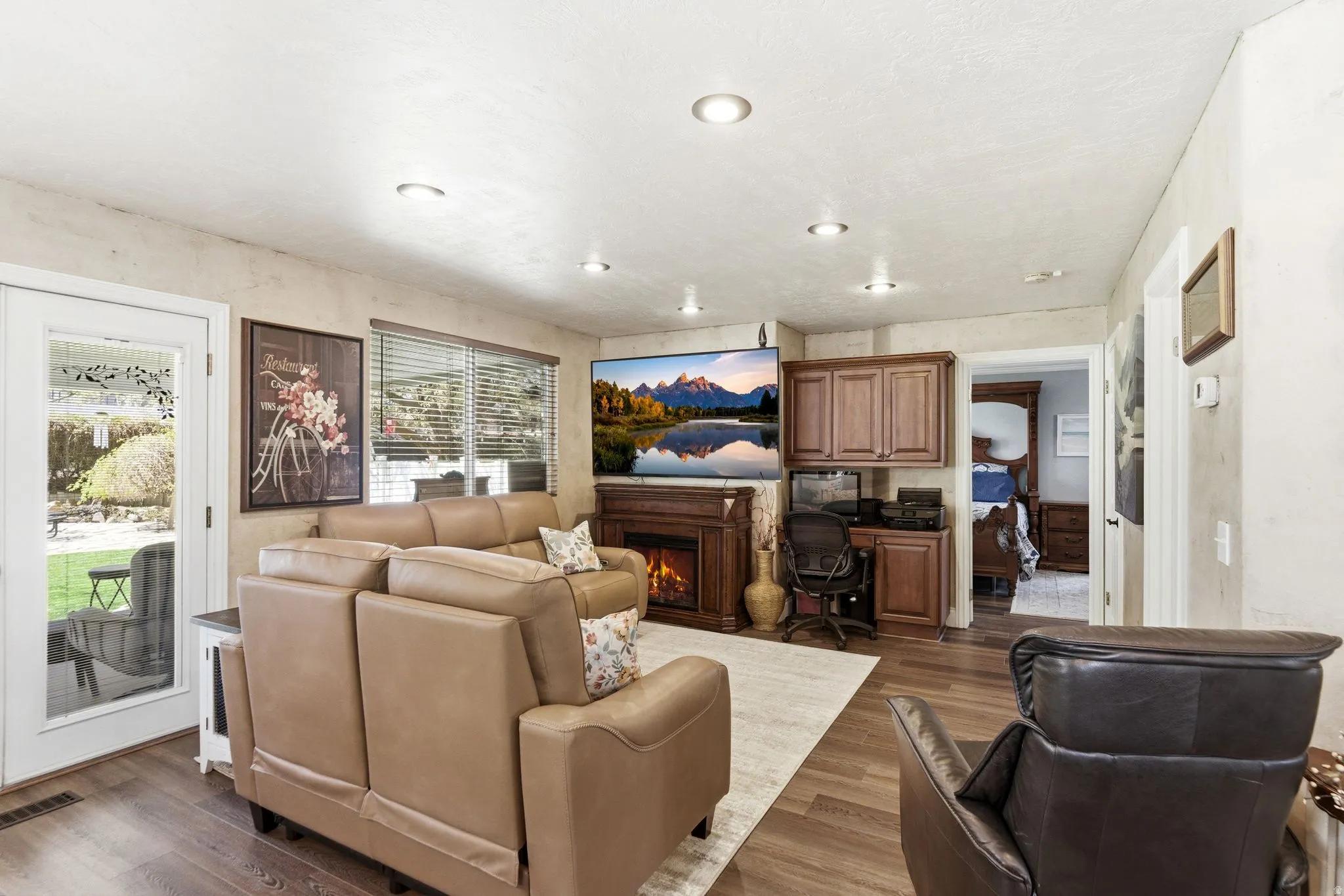 Living room with a warm lit fireplace and wood finished floors