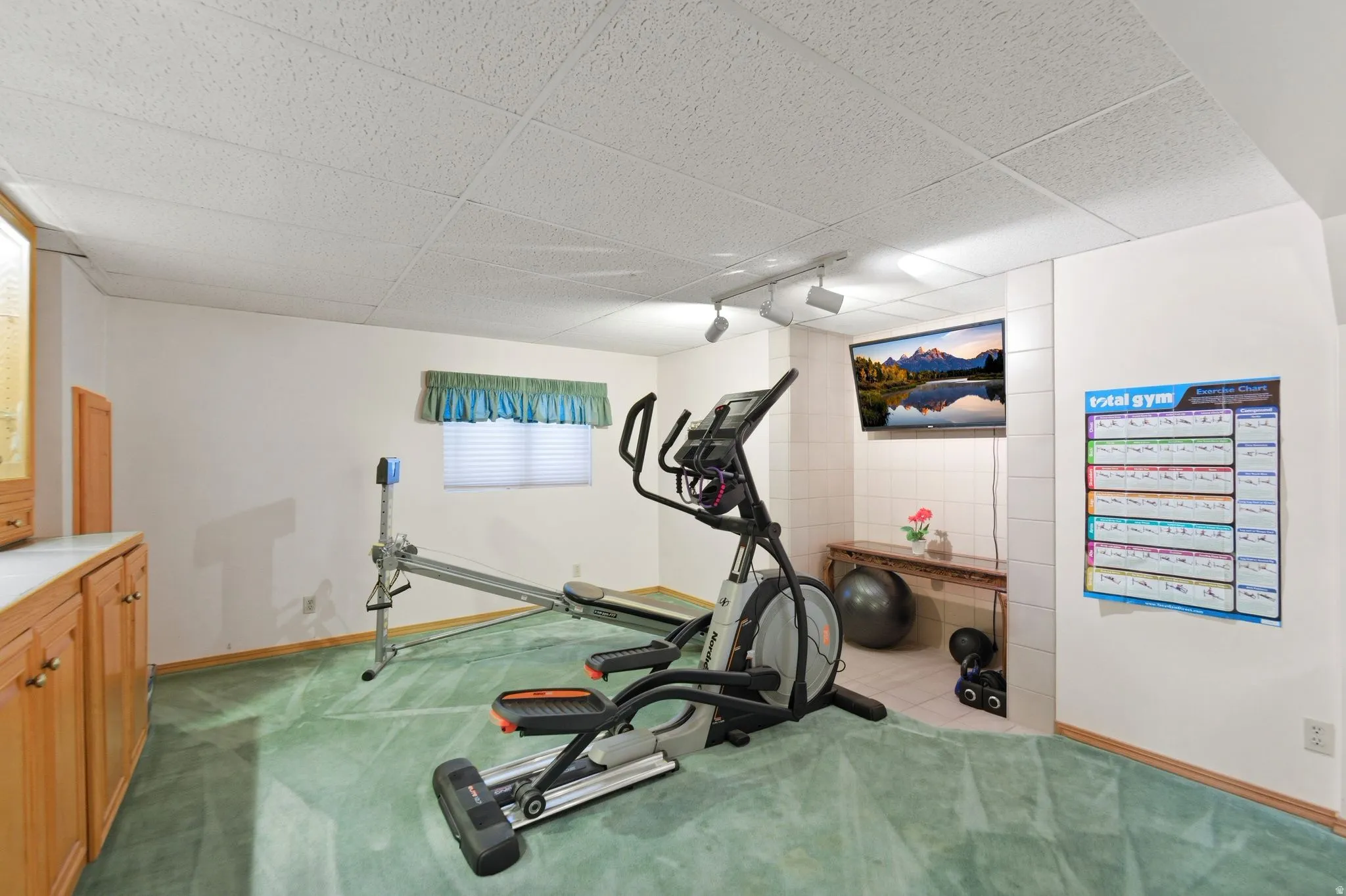 Exercise area with a paneled ceiling and light colored carpet