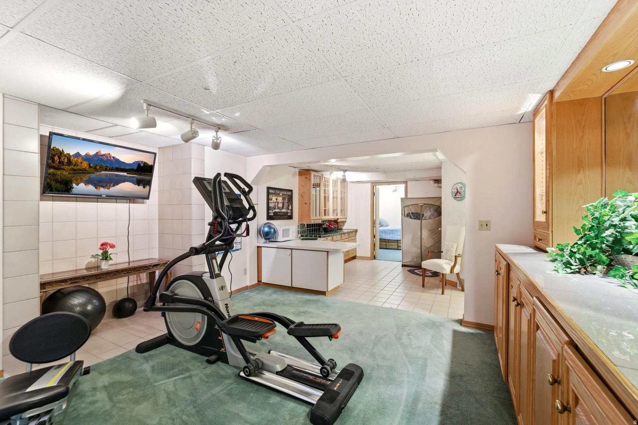 Exercise area with light tile patterned floors, light carpet, rail lighting, and a paneled ceiling