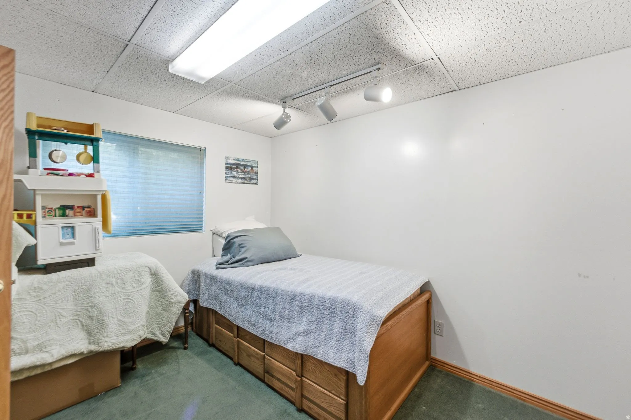 Bedroom with dark colored carpet, rail lighting, and a paneled ceiling