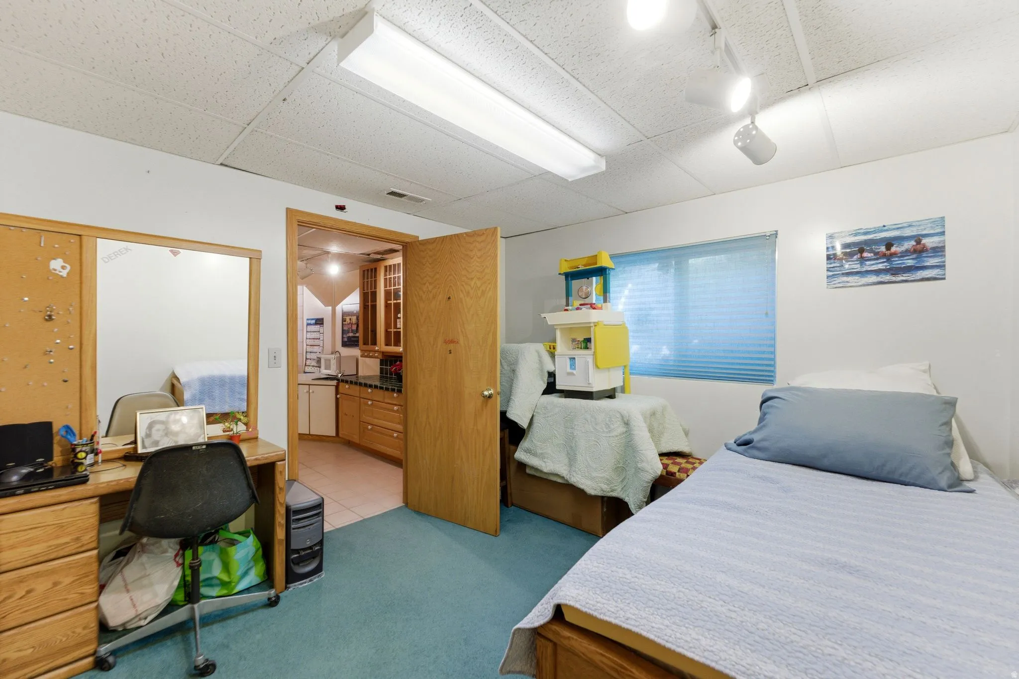 Bedroom with an office area, light carpet, and a paneled ceiling