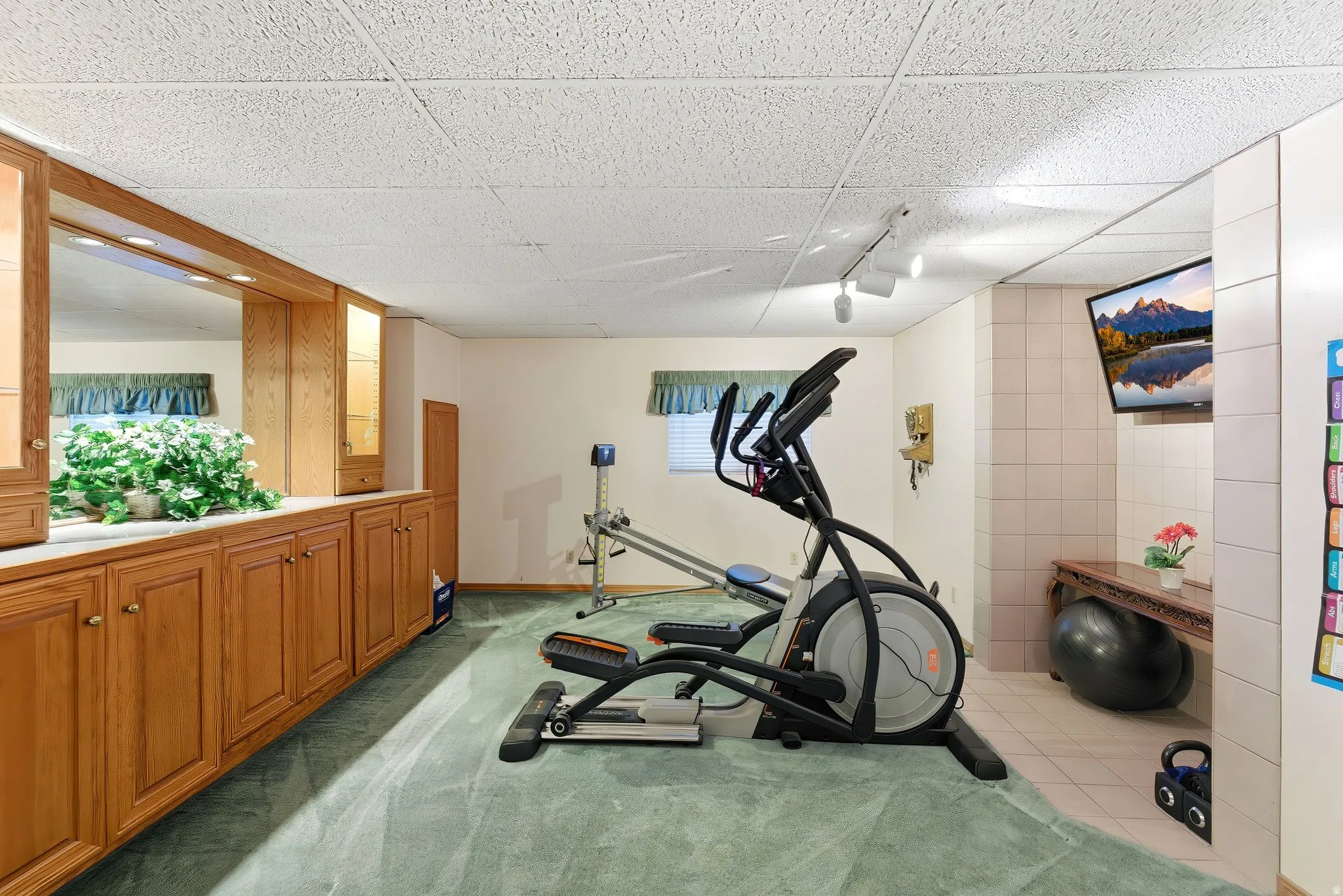 Exercise room with a paneled ceiling and light carpet