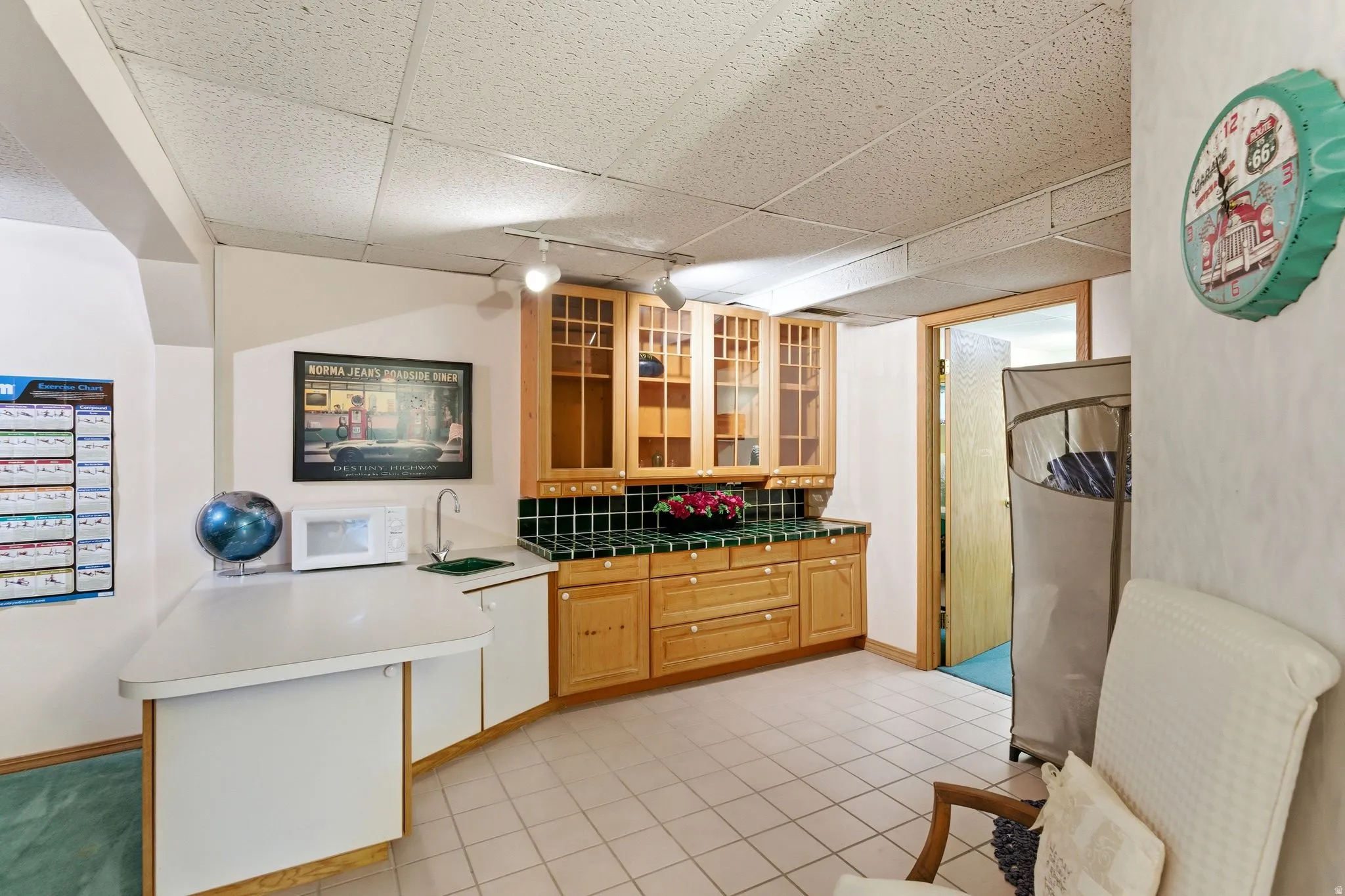 Kitchen featuring a peninsula, white microwave, rail lighting, a drop ceiling, and light tile patterned floors