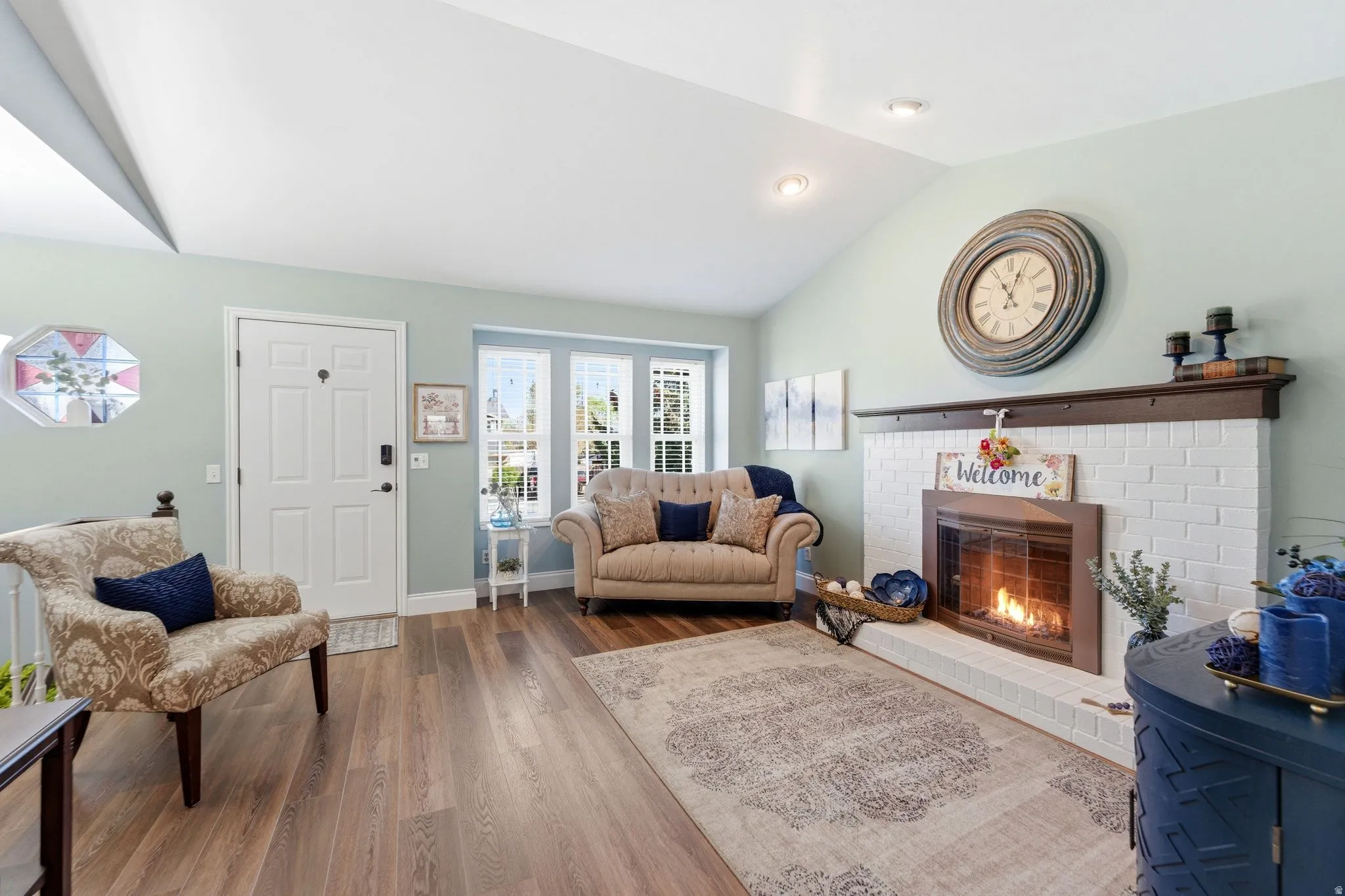Living area featuring lofted ceiling, a brick fireplace, and wood finished floors