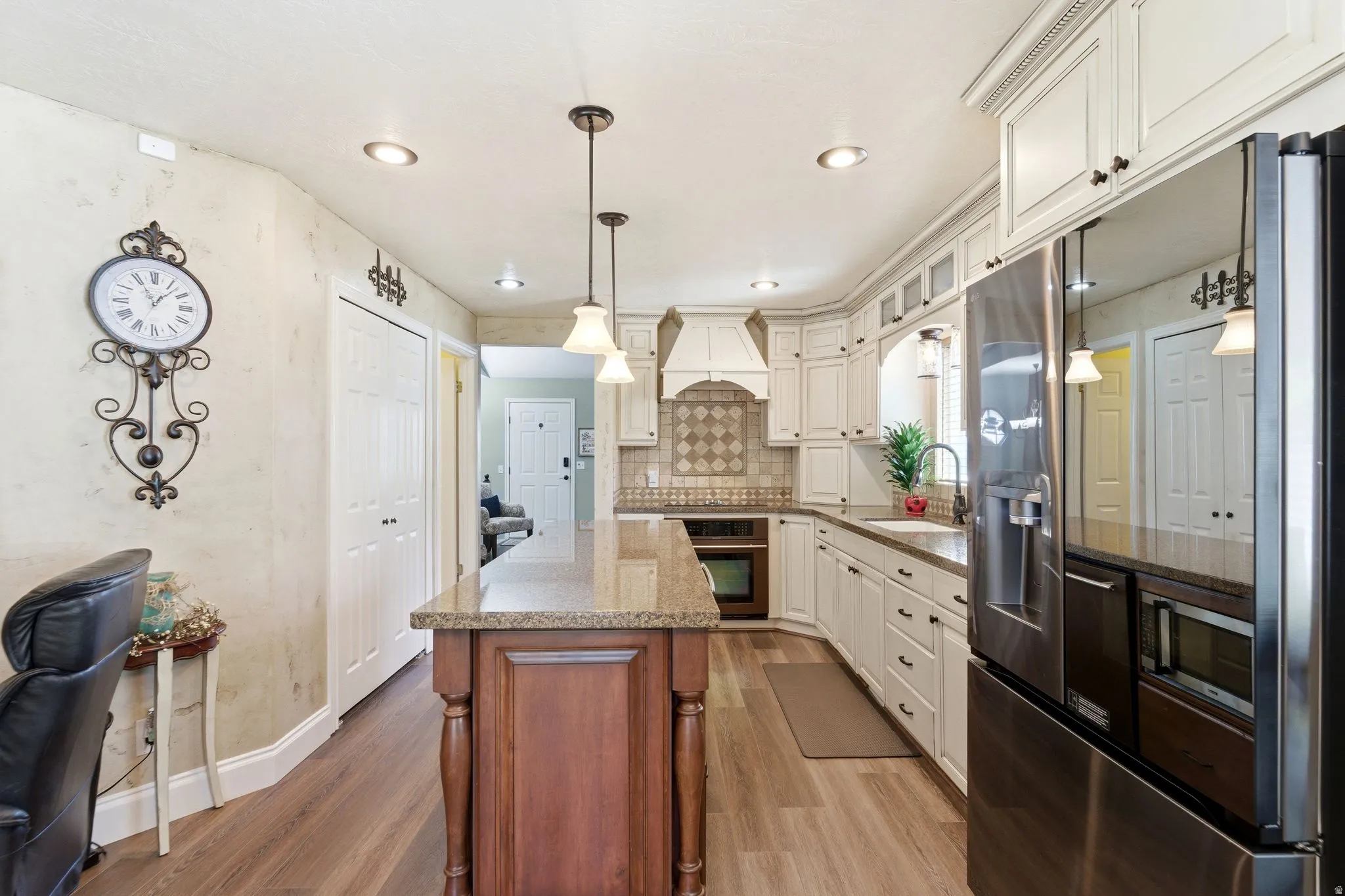 Kitchen with stainless steel appliances, light stone counters, glass fronted cabinets, backsplash, and light wood-style floors