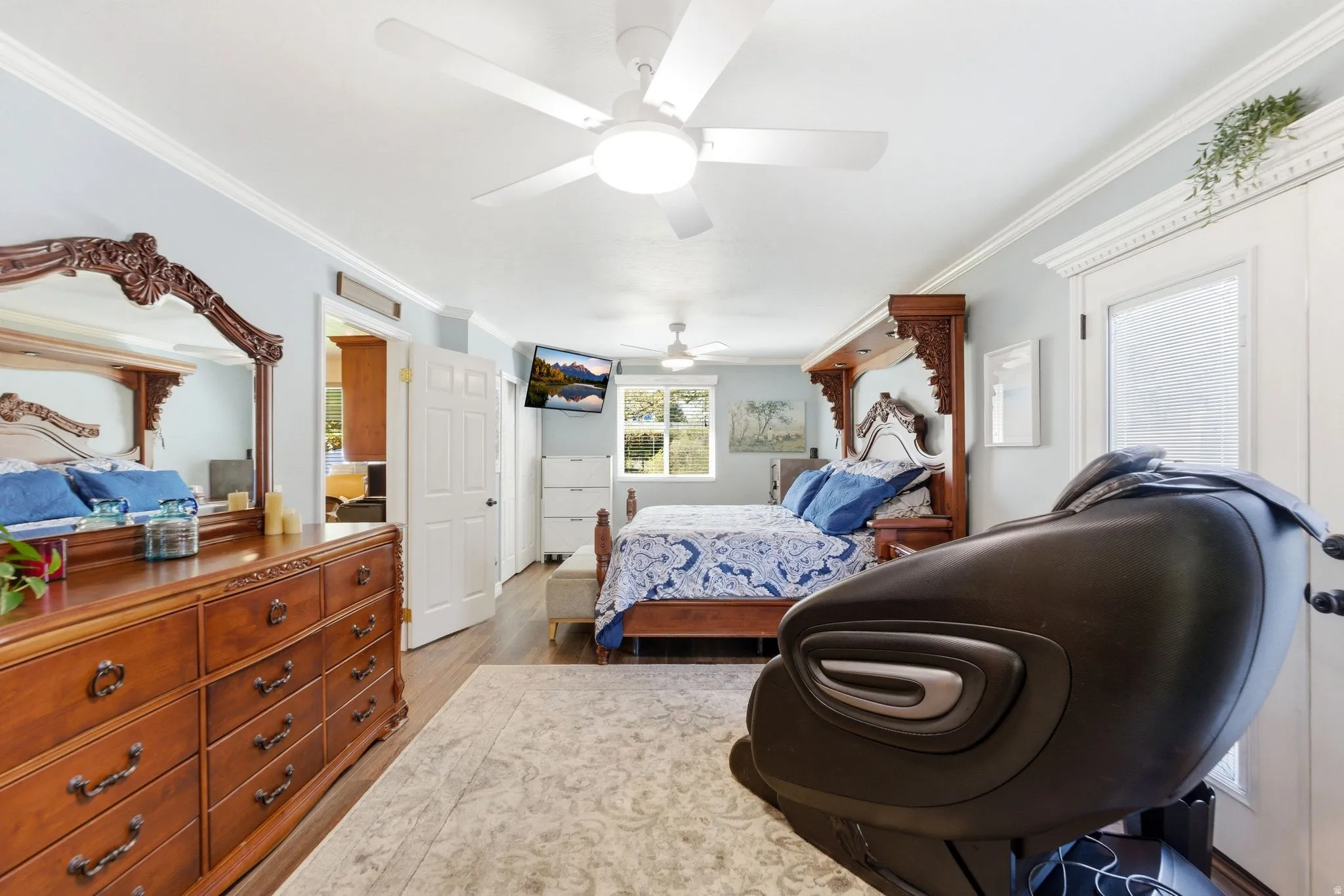 Bedroom featuring crown molding, light wood-style floors, and a ceiling fan