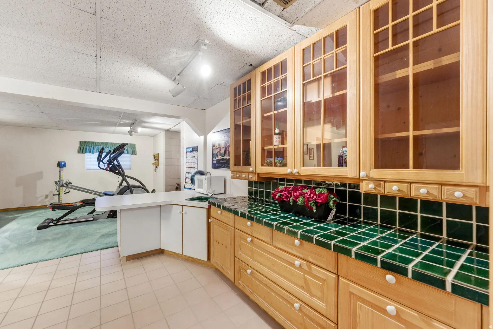 Kitchen with a peninsula, tile counters, rail lighting, a paneled ceiling, and backsplash