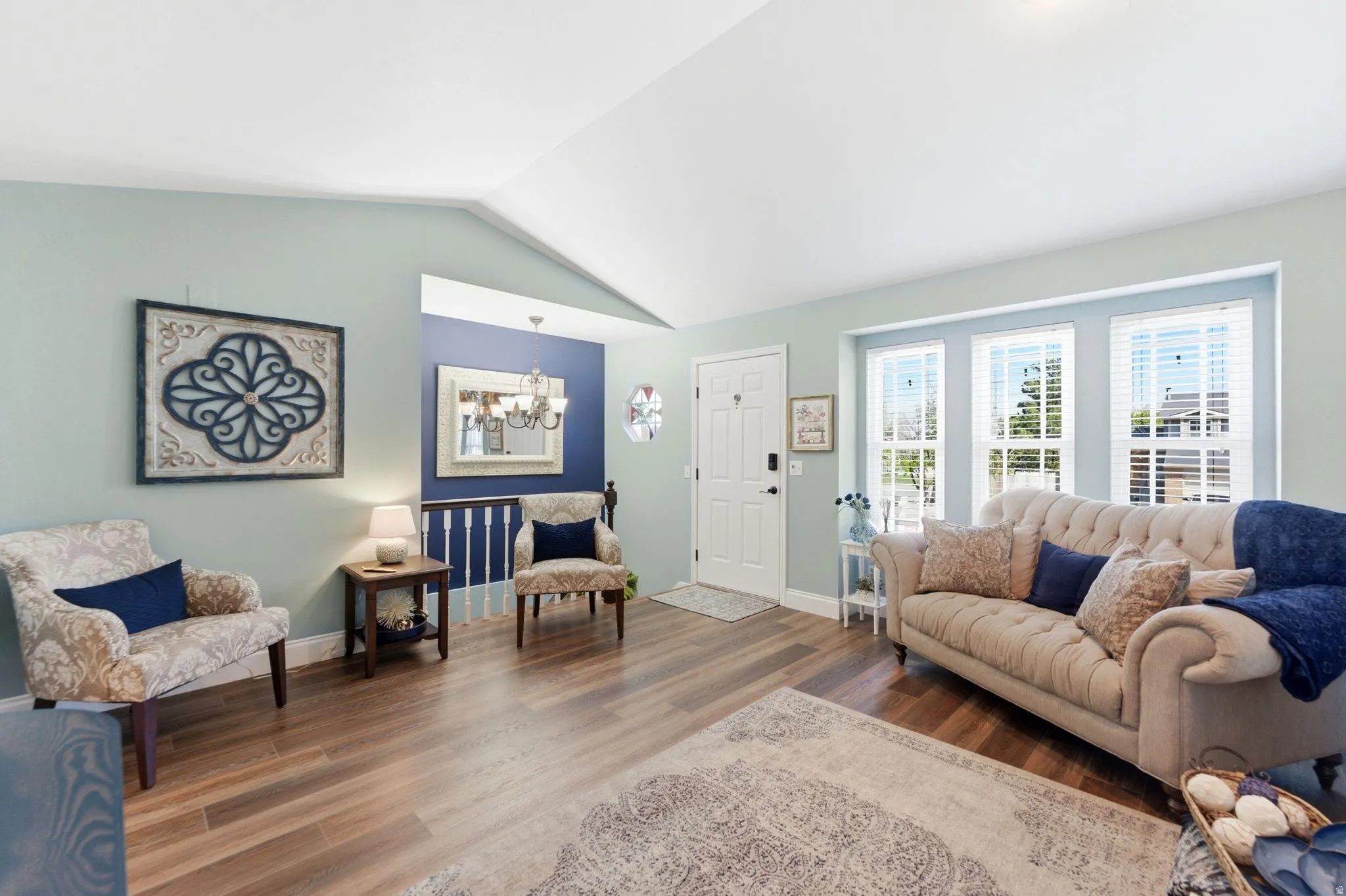 Living room with a chandelier, wood finished floors, and lofted ceiling