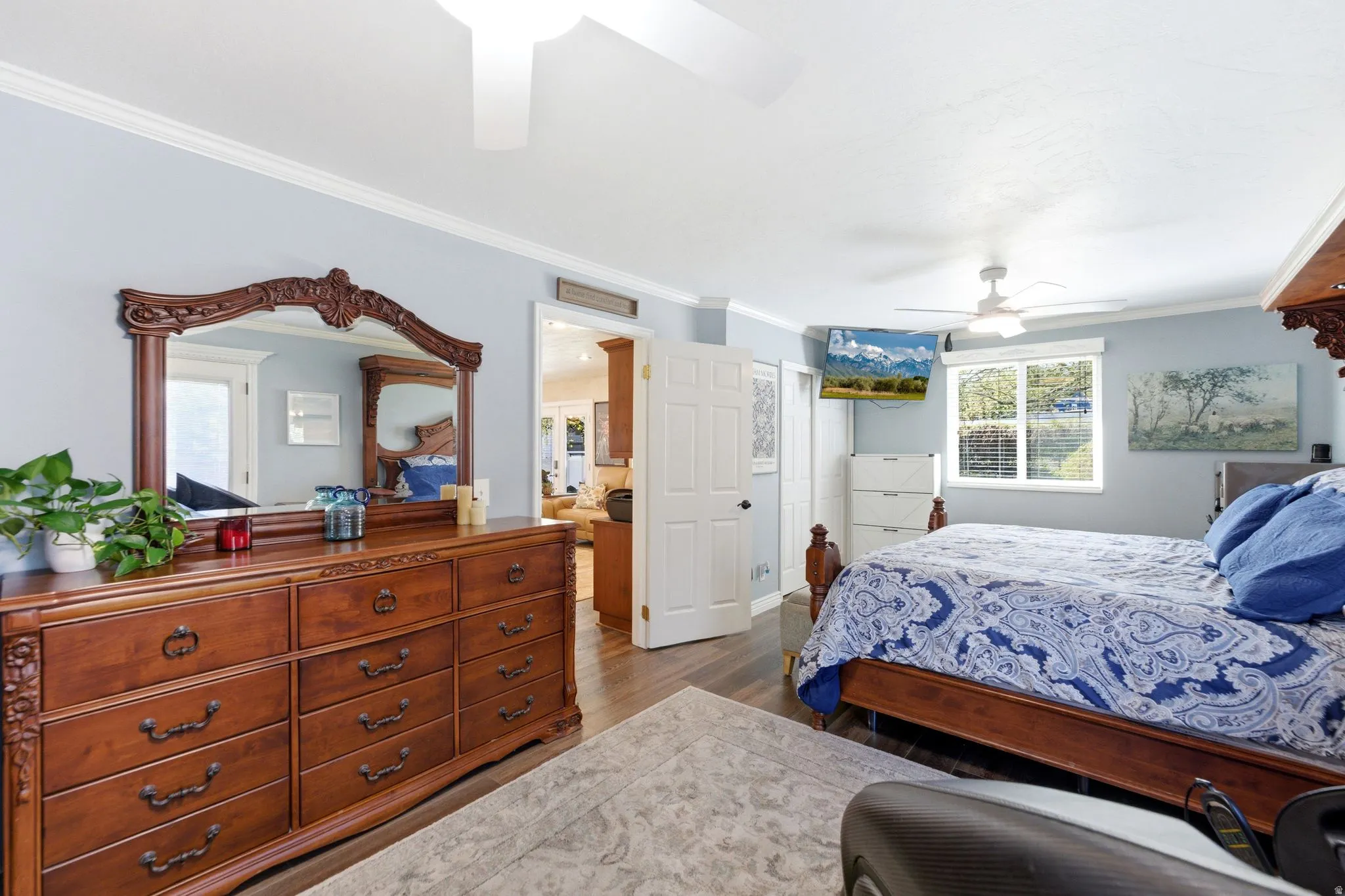 Bedroom with ceiling fan, ornamental molding, dark wood-style flooring, and a closet