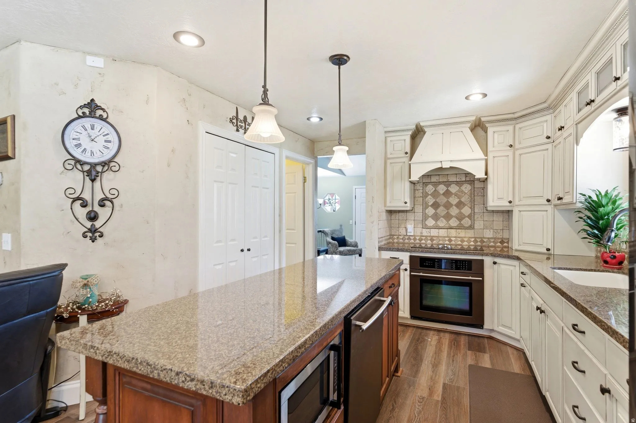 Dual tone kitchen with dark stone counters, stainless steel appliances, a kitchen island, pendant lighting, and dark wood-style floors