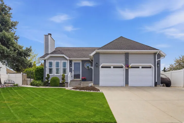 Ranch-style home featuring an attached garage, a shingled roof, concrete driveway, and a chimney