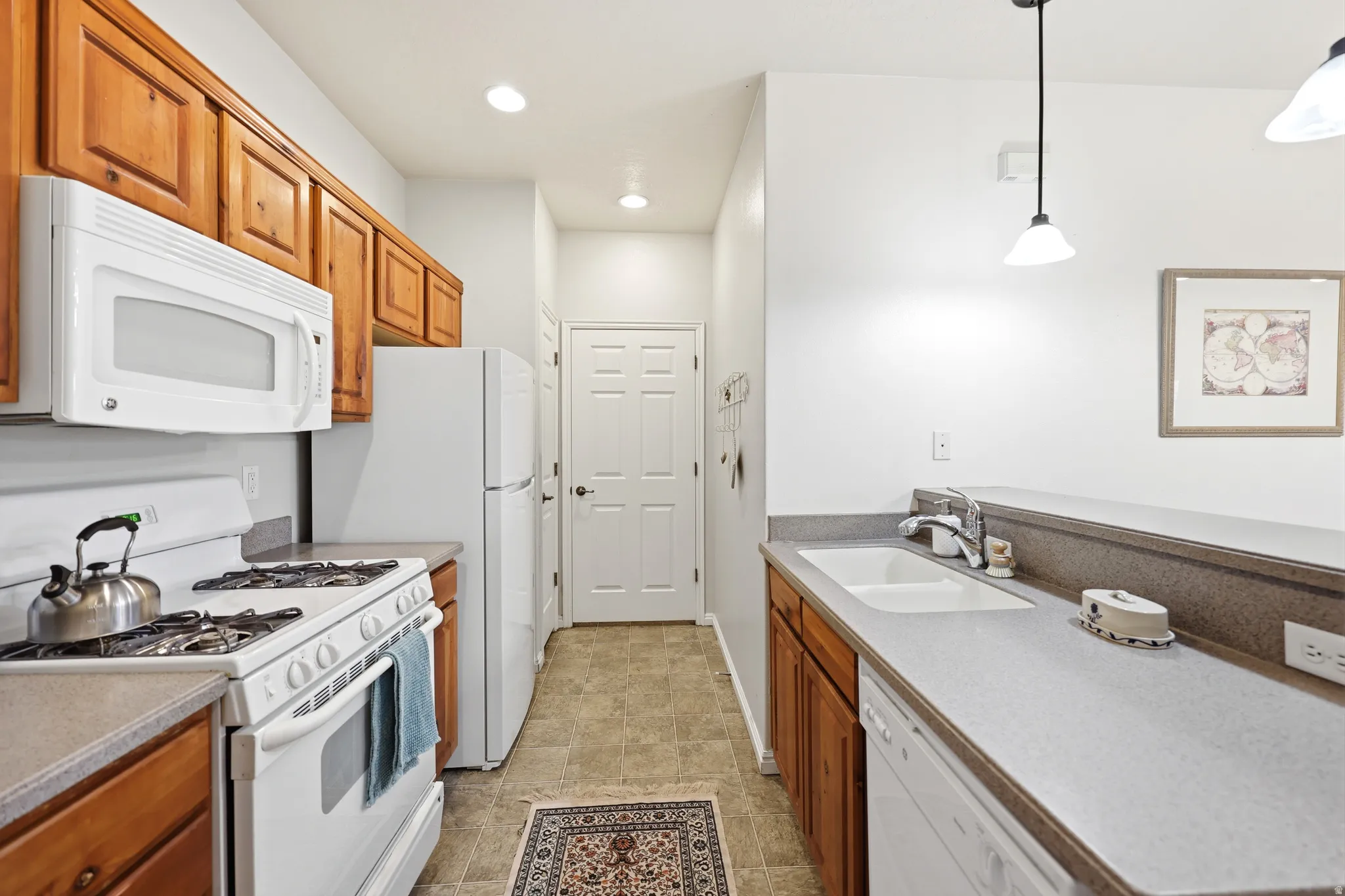 Kitchen featuring white appliances, wood finish cabinets, and decorative light fixtures