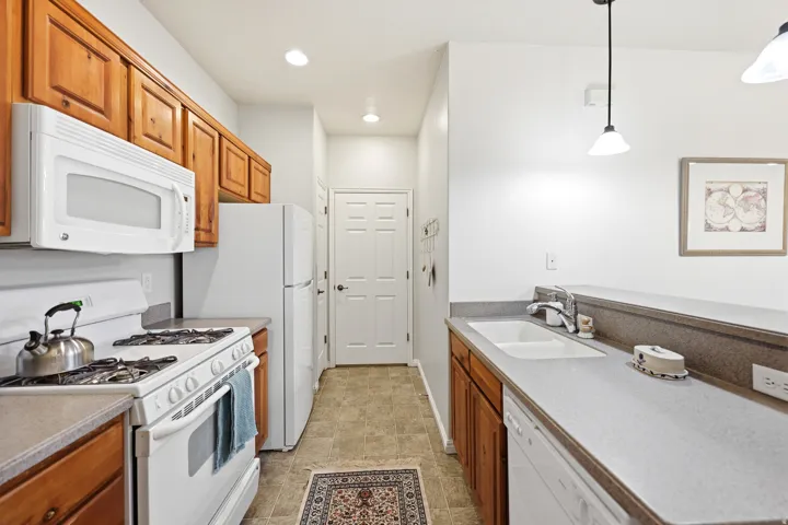 Kitchen featuring white appliances, wood finish cabinets, and decorative light fixtures