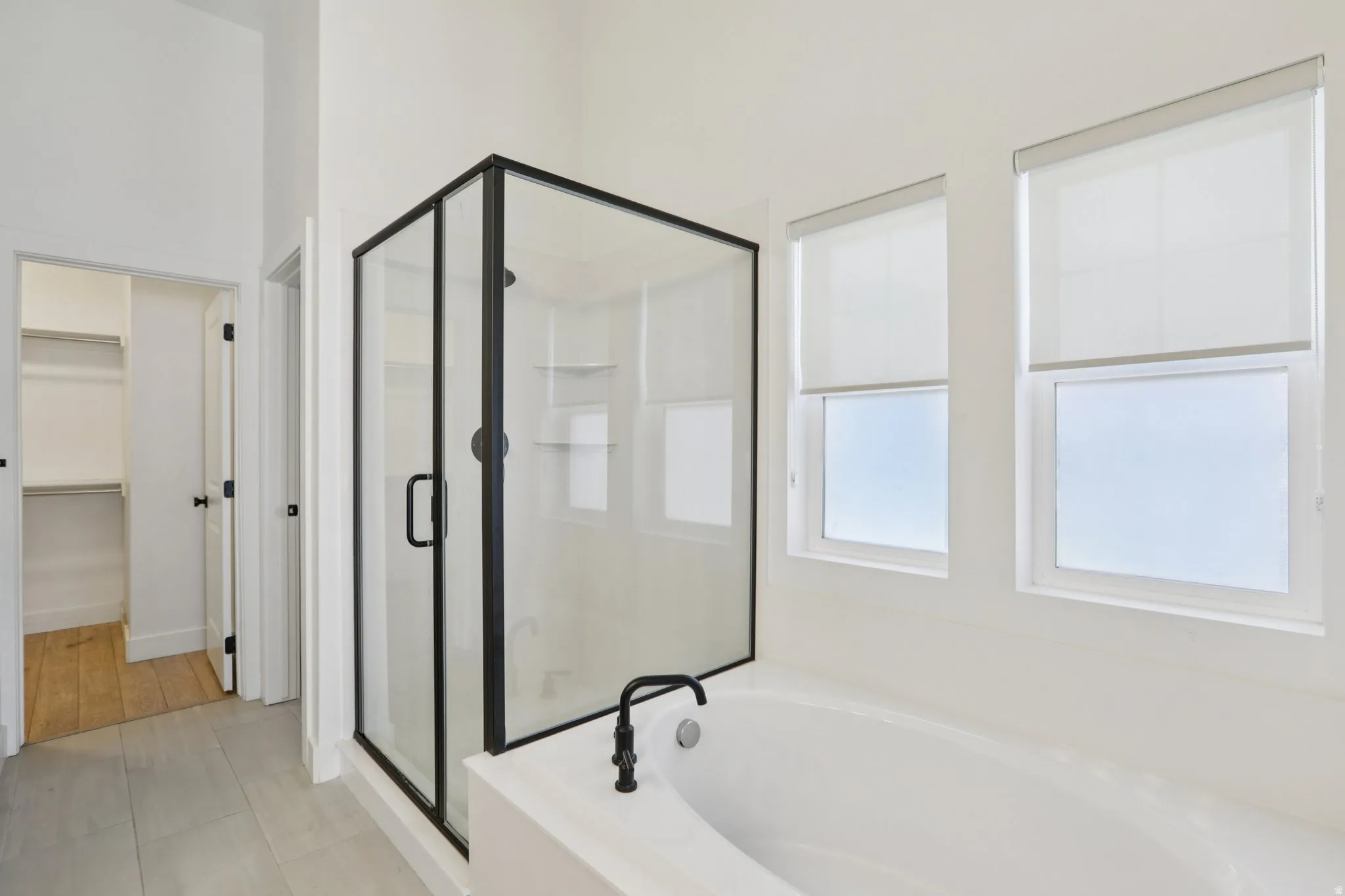 Bathroom with a shower stall, a walk in closet, a garden tub, and light tile patterned floors