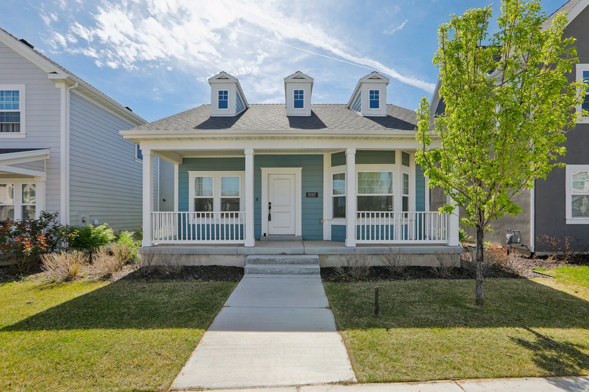 View of front of property featuring a porch, a shingled roof, and a front yard