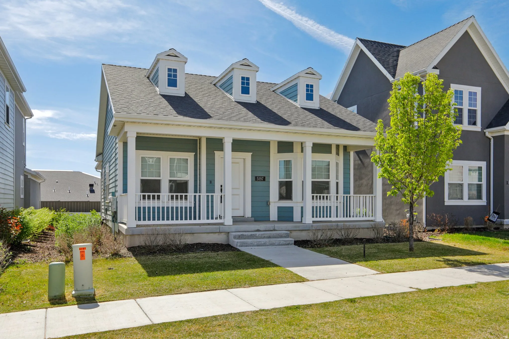 View of front facade featuring roof with shingles, covered porch, and a front lawn