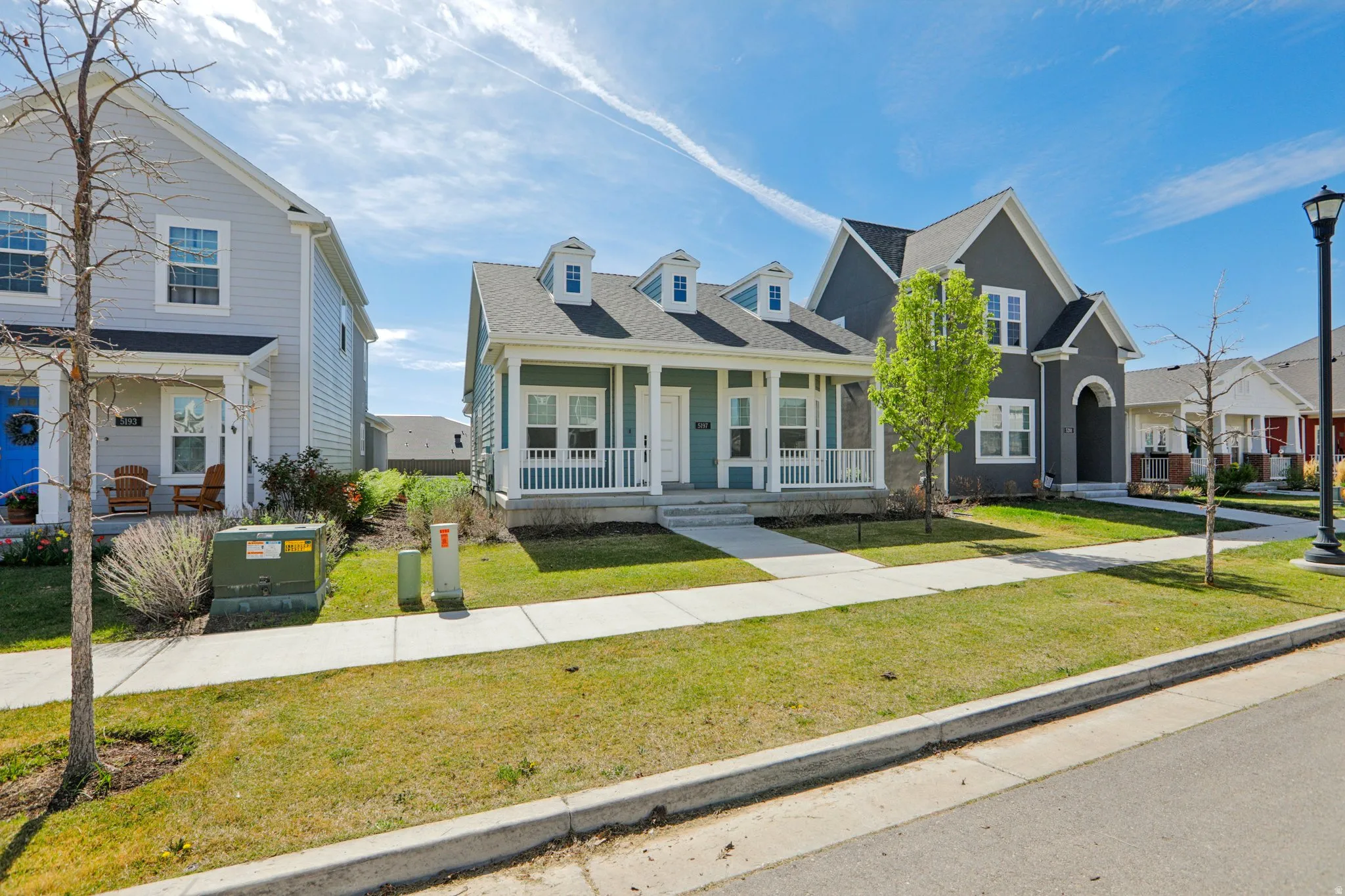View of front facade with covered porch, a front yard, and a shingled roof