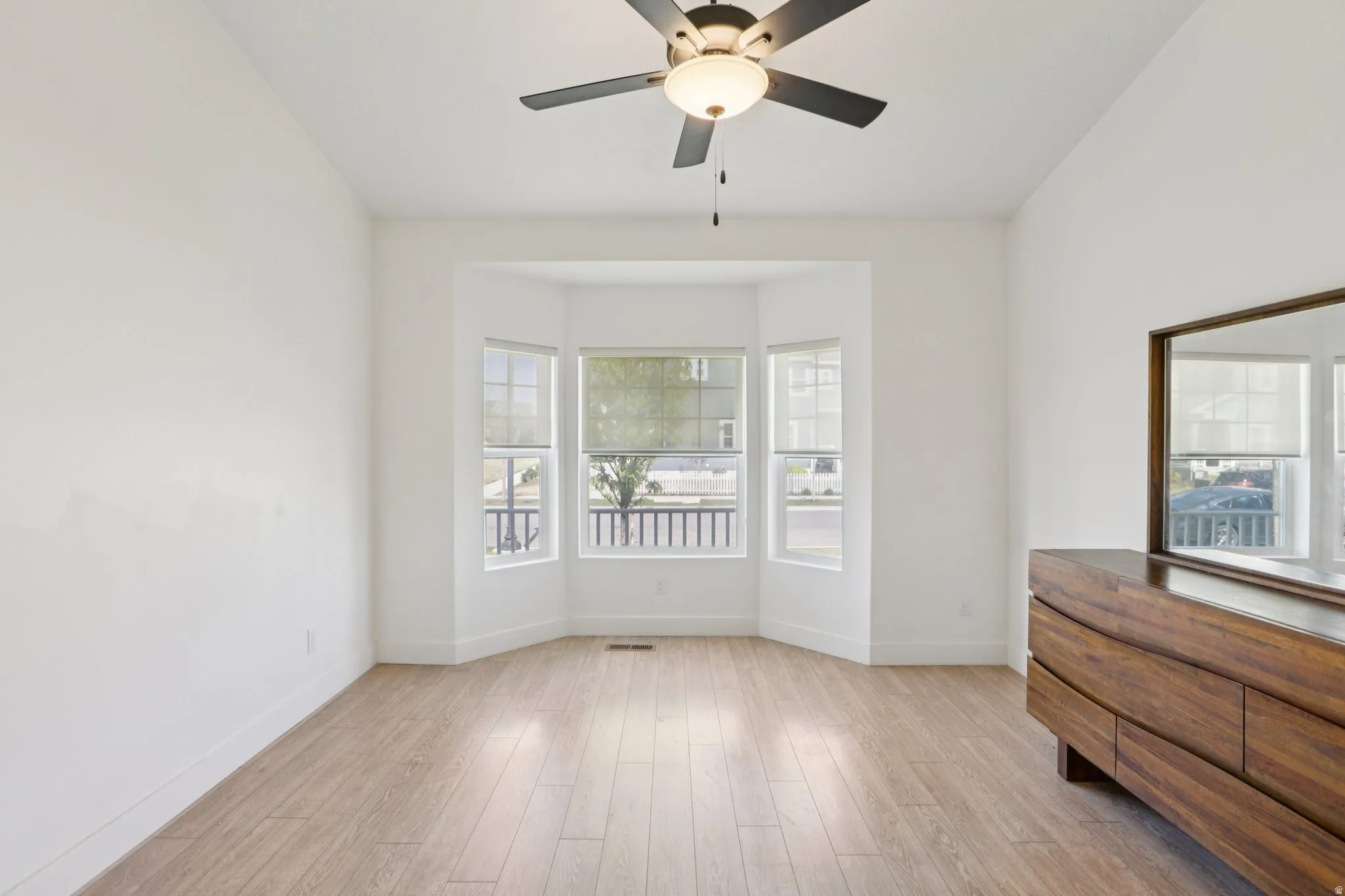 Empty room with light wood-type flooring and a ceiling fan