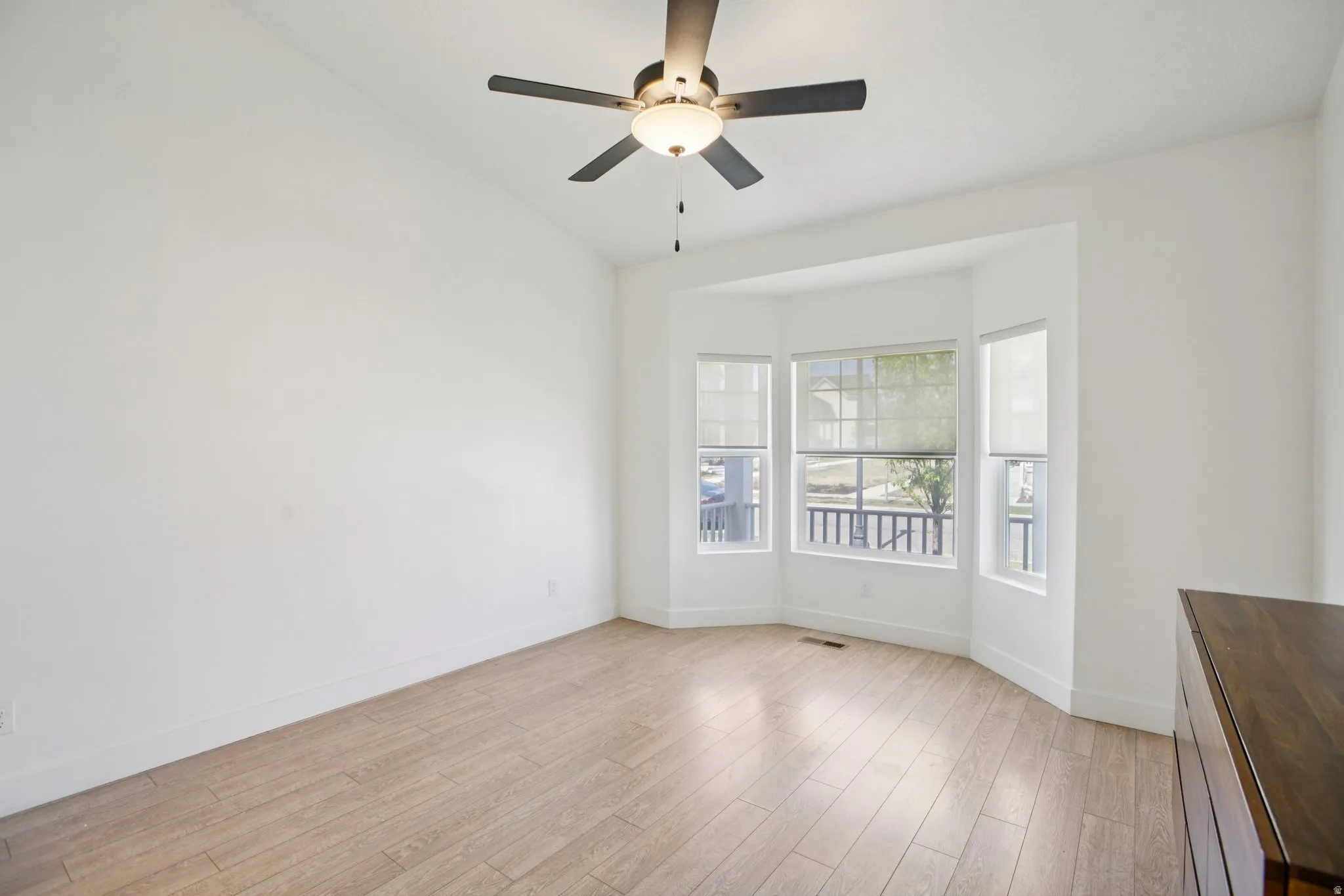 Empty room with light wood-type flooring, a ceiling fan, and lofted ceiling