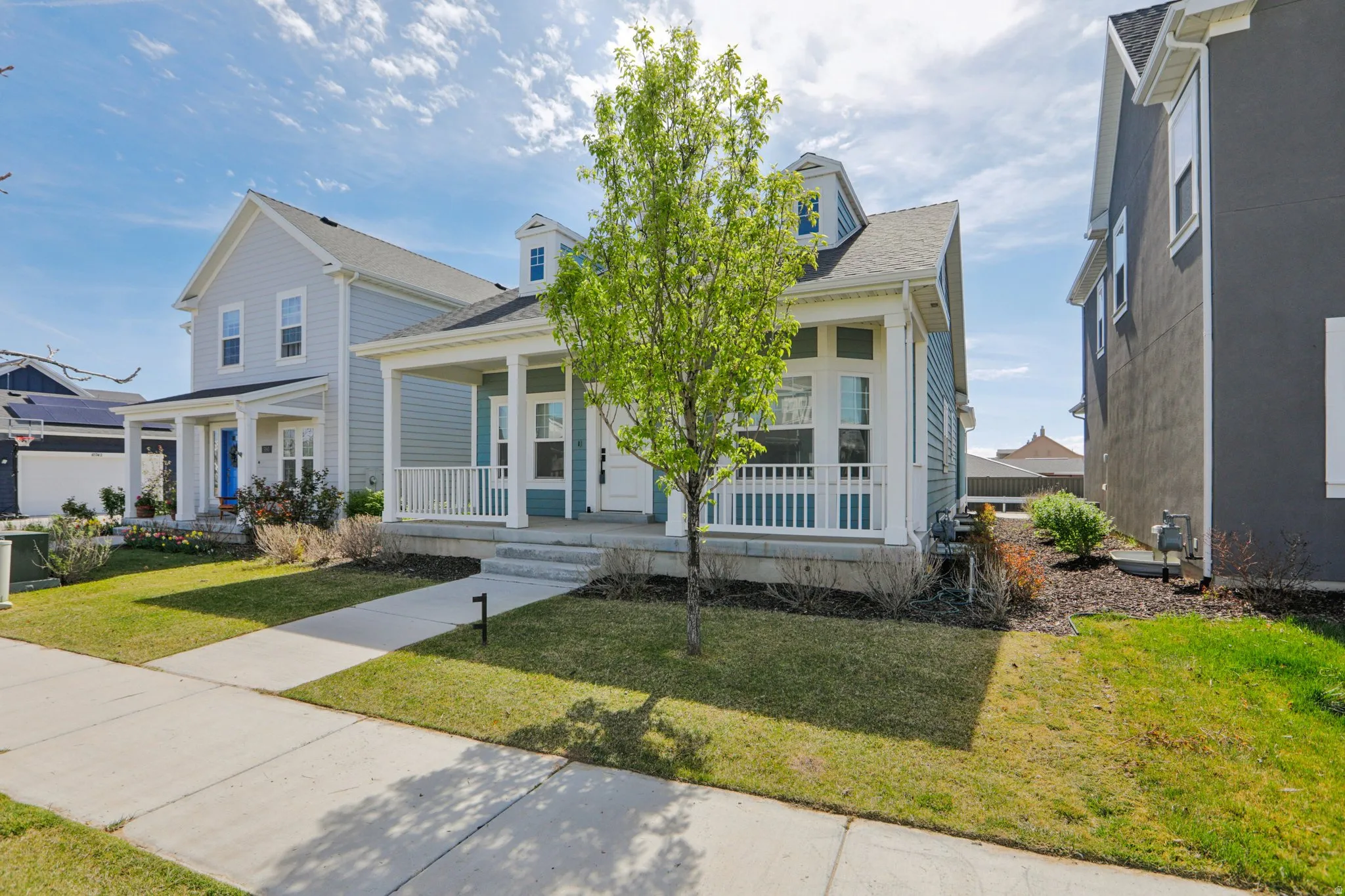 View of front of property featuring covered porch, a front yard, and roof with shingles
